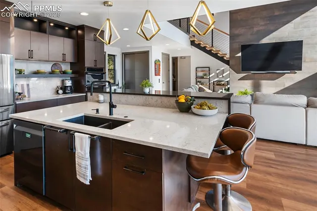 a kitchen with stainless steel appliances granite countertop a sink a stove and a wooden floor