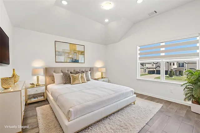 a bedroom with a large bed a flat tv screen and a dresser