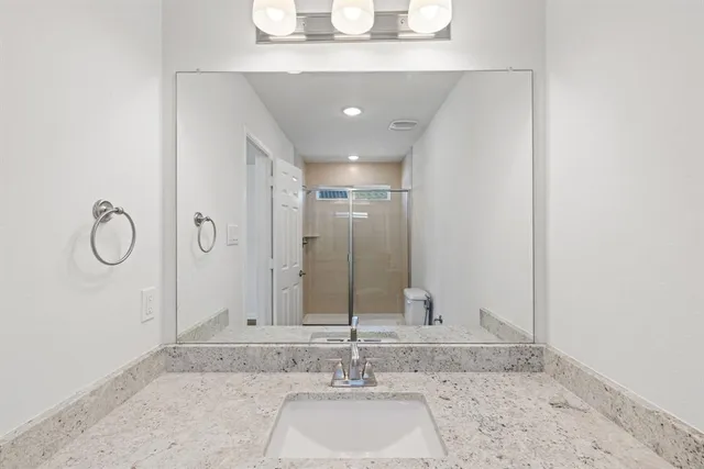 a bathroom with a granite countertop sink and a mirror