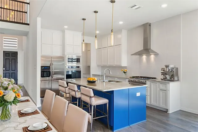 a kitchen with stainless steel appliances granite countertop a sink a stove a refrigerator and island with wooden floor