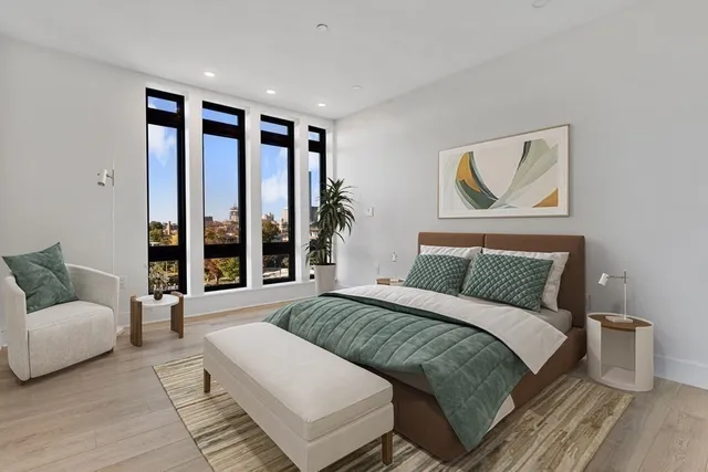 a bedroom with a large bed couch and a large window