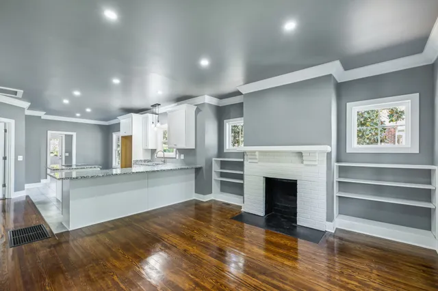 a large kitchen with granite countertop a stove top oven a sink and a wooden floors