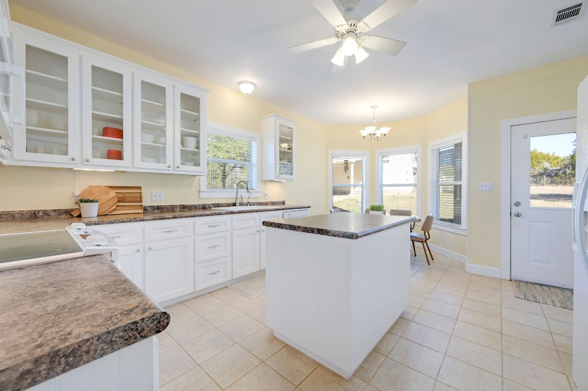 881 Saddle Ridge Drive Wimberley, TX 78676 - Photo 10 of 30 a large kitchen with kitchen island granite countertop a sink a stove a dining table and chairs