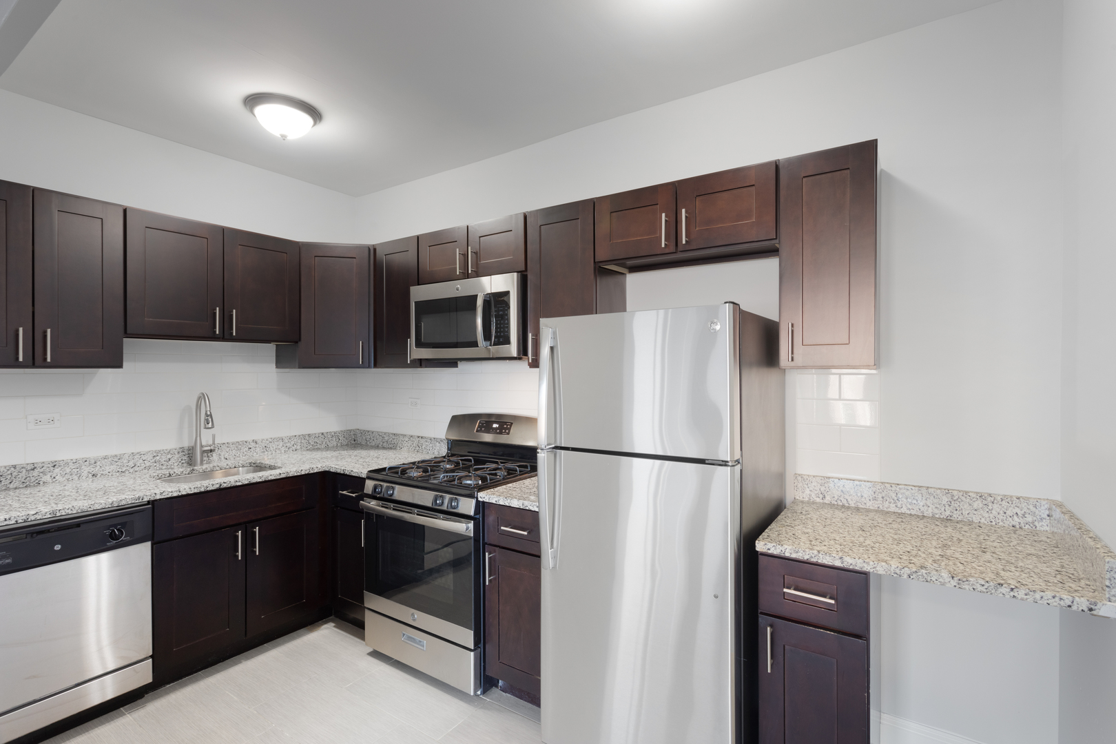 1608 West Sherwin Avenue, Unit 705 Chicago, IL 60626 - Photo 3 of 10 a kitchen with stainless steel appliances granite countertop a refrigerator stove a sink dishwasher and microwave