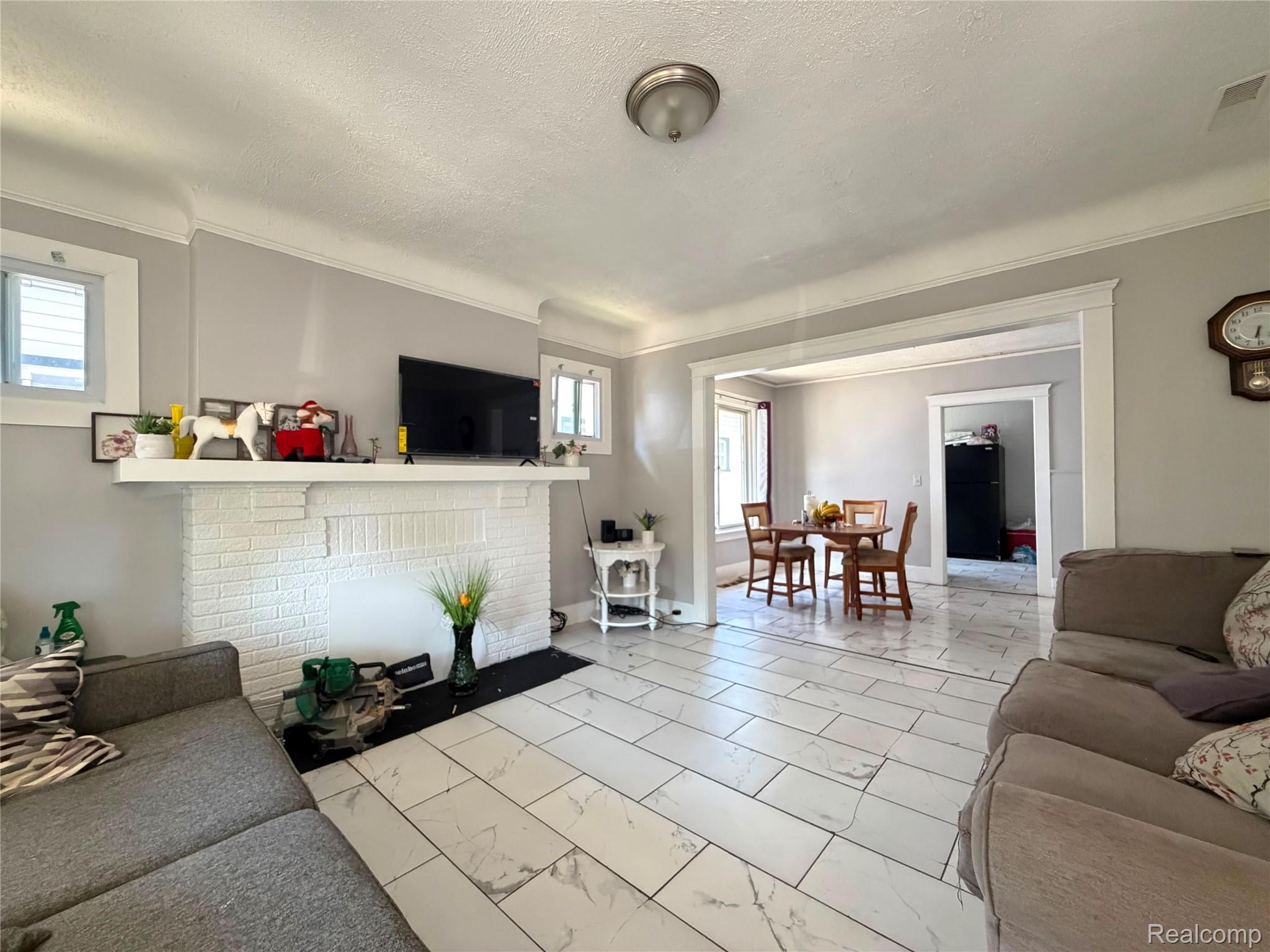9940 Manor Detroit, MI 48204 - Photo 7 of 16 Spacious living area featuring white tile flooring, a white brick fireplace with a mantel, and crown molding