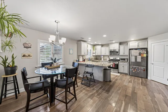 a kitchen with a dining table chairs stainless steel appliances and cabinets