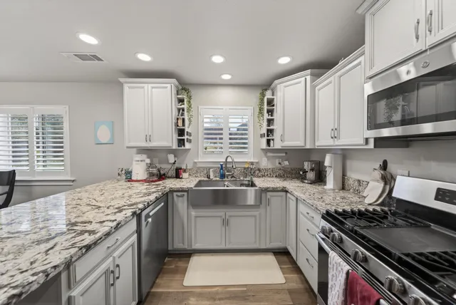 a kitchen with stainless steel appliances granite countertop a sink stove and cabinets