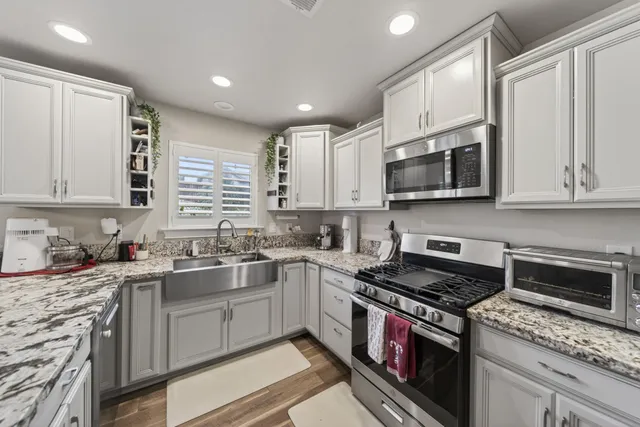 a kitchen with stainless steel appliances granite countertop a sink stove microwave and refrigerator