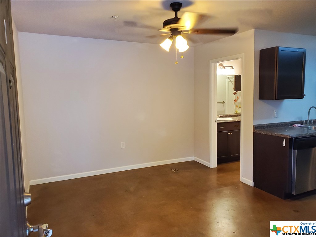 an empty room with a flat screen tv and kitchen view