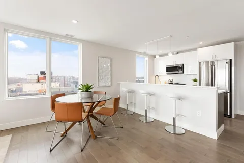 a kitchen with stainless steel appliances a dining table chairs refrigerator and sink