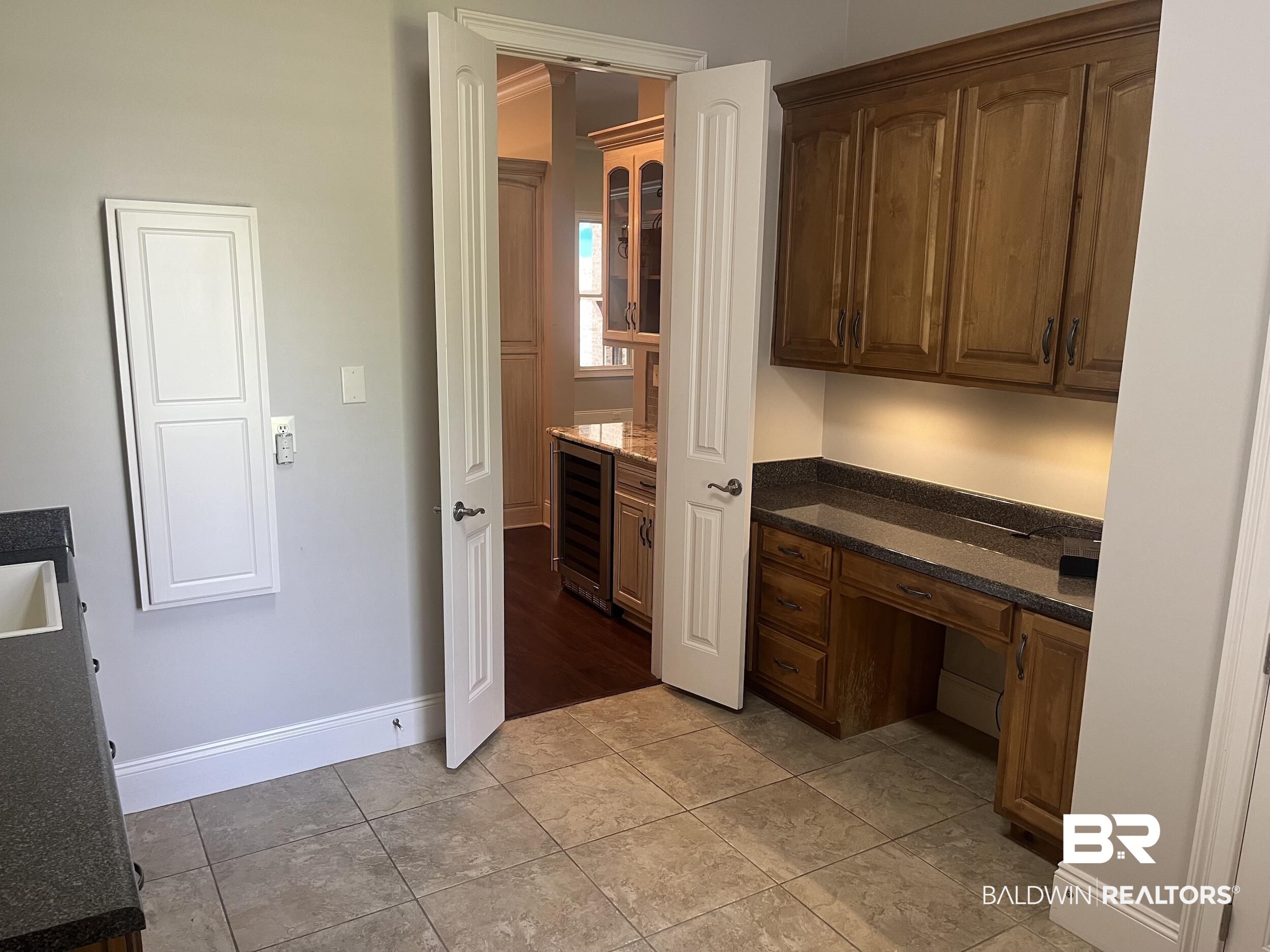 565 Falling Water Boulevard Fairhope, AL 36532 - Photo 14 of 27 Unfurnished office with light tile patterned flooring, built in desk, and wine cooler