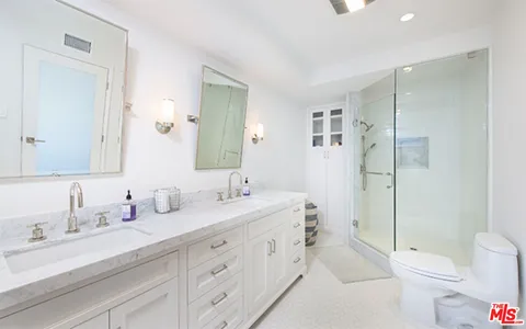 a bathroom with a toilet a sink a mirror a shower a vanity and window