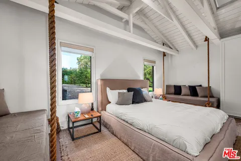 a large white bed sitting in a bedroom next to a window