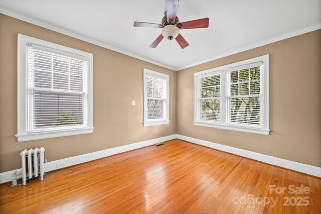 a view of an empty room with a window and wooden floor