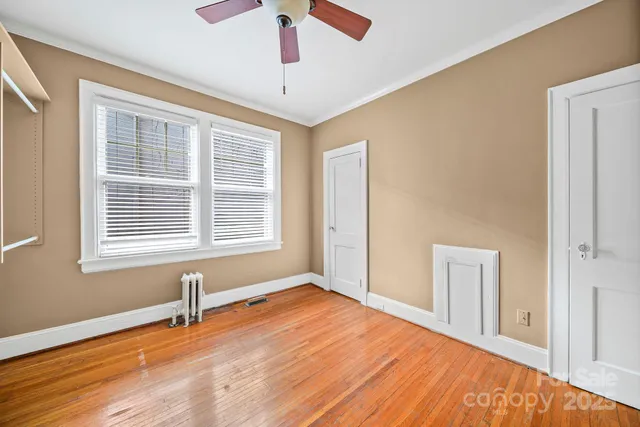 a view of an empty room with a window and wooden floor