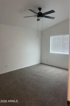 an empty room with a window and a fan