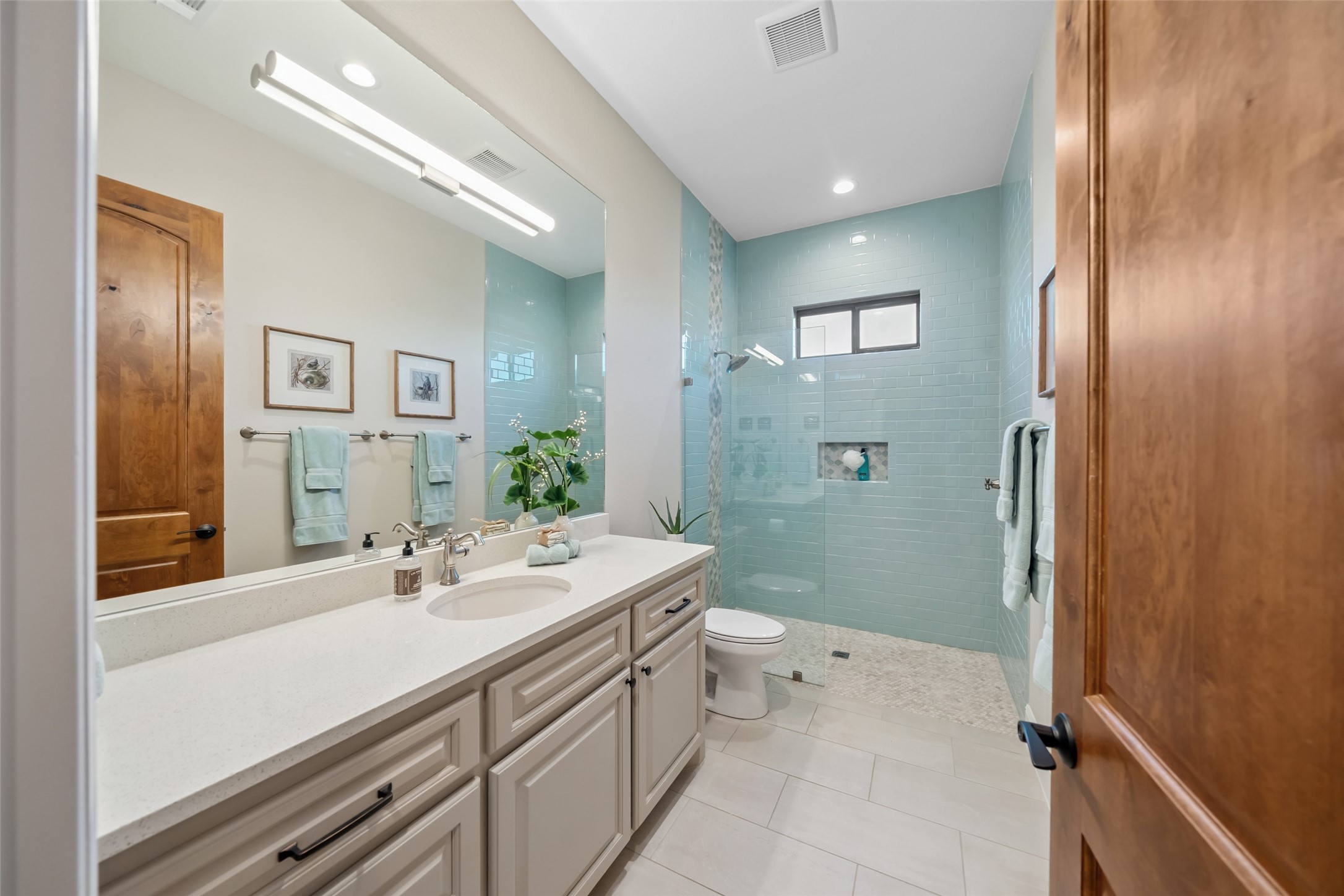 30163 High Spirit Ranch Road Hempstead, TX 77445 - Photo 28 of 47 Thoughtfully designed with a walk-in
shower clad in soft blue subway tile,
this centrally located bathroom sits
between the current study and guest
bedroom. It features a long quartz
vanity, generous cabinetry, and
natural light from a transom window
above the shower.