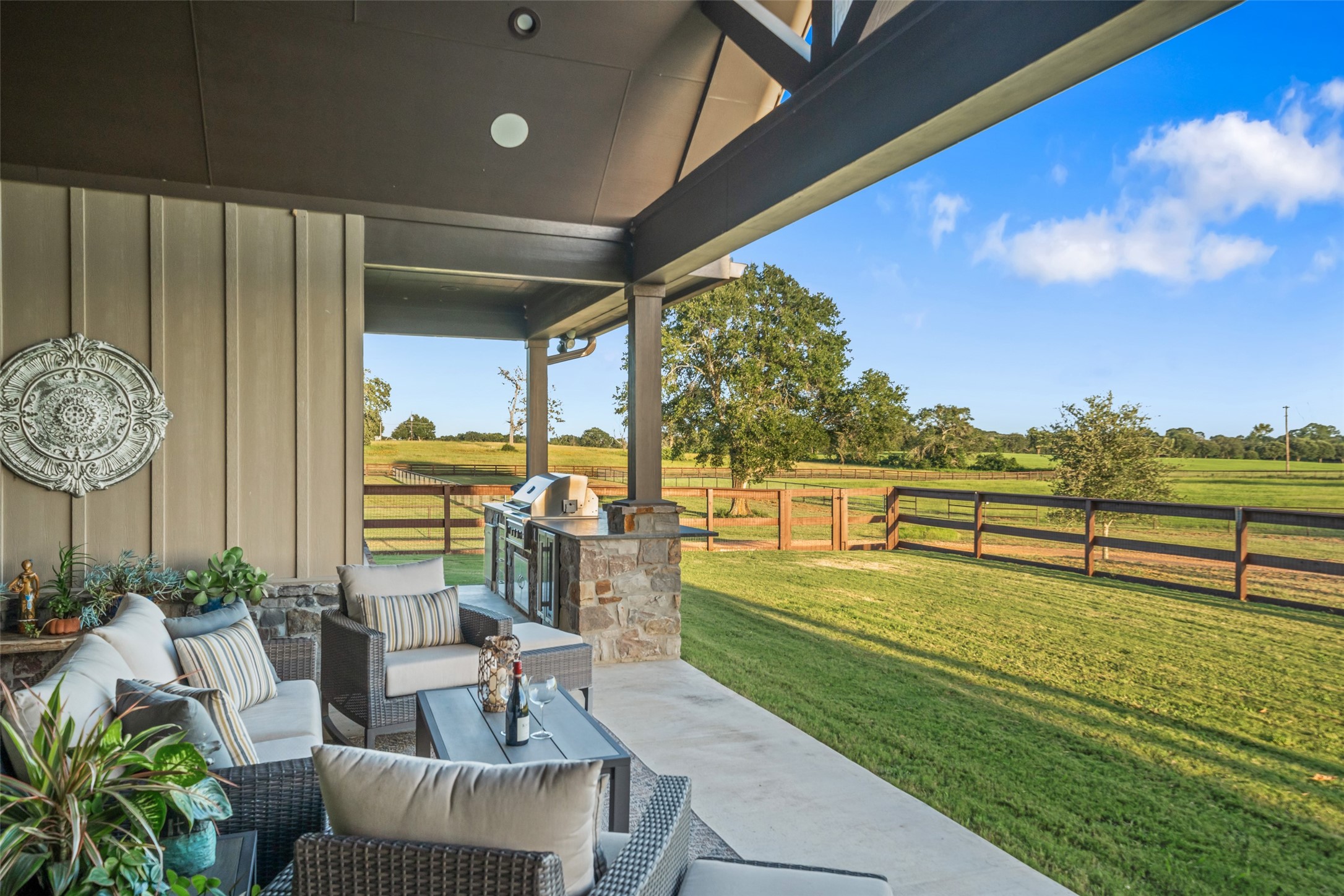 30163 High Spirit Ranch Road Hempstead, TX 77445 - Photo 32 of 47 This outdoor living area seamlessly
blends comfort and function,
featuring an outdoor kitchen with a
beverage fridge, and peaceful
countryside backdrop—ideal for
hosting or relaxing.