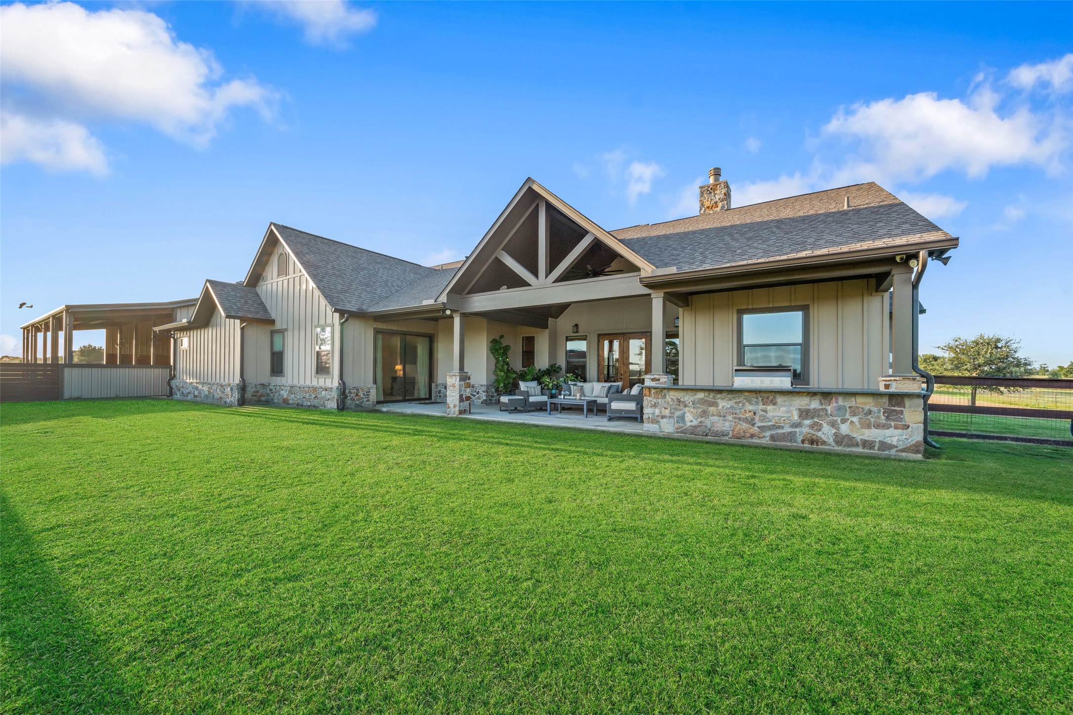 30163 High Spirit Ranch Road Hempstead, TX 77445 - Photo 34 of 47 The back elevation of the home
showcases the architectural beauty
of its pitched rooflines and
stonework, with a wide patio that
connects seamlessly to the
surrounding landscape.