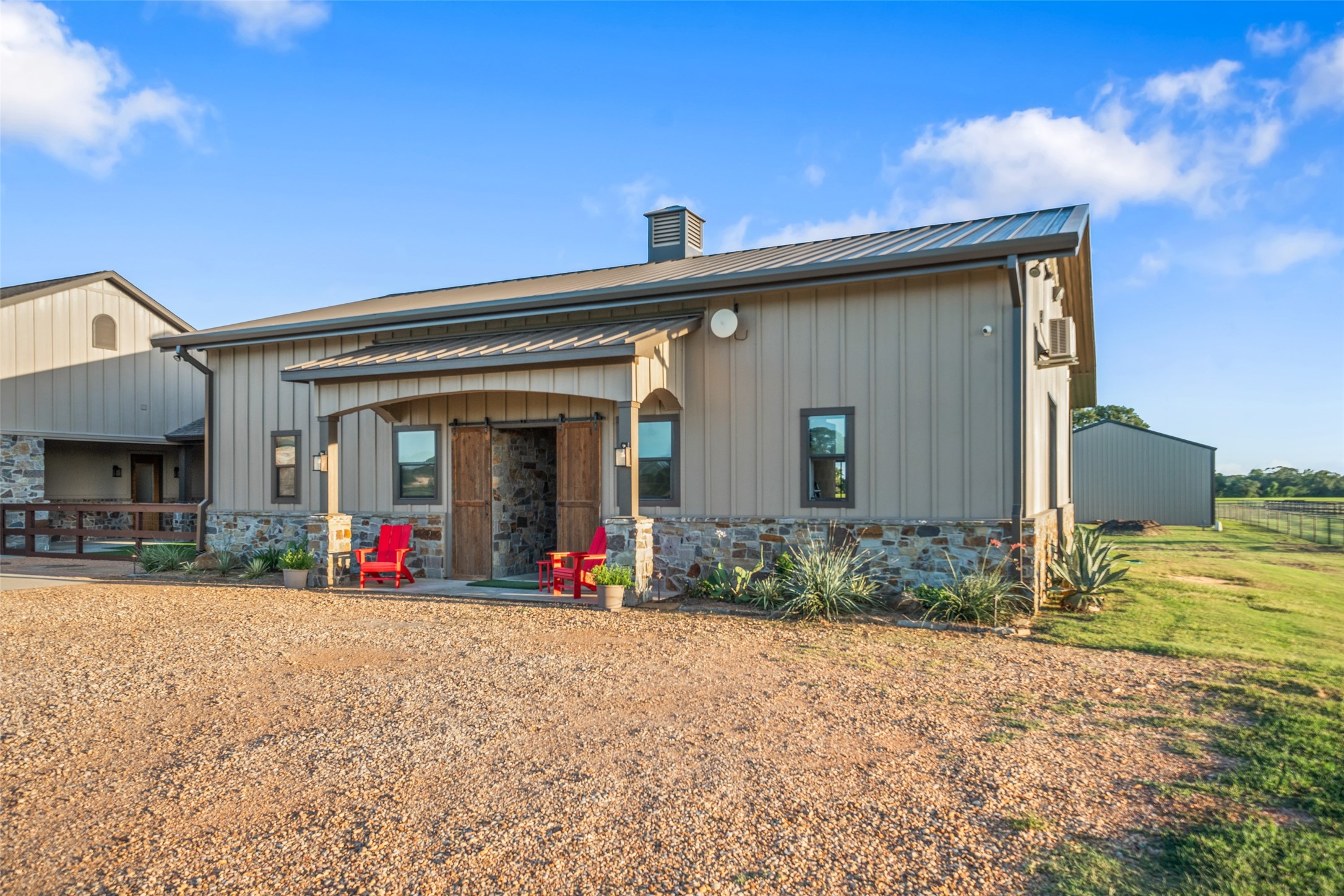 30163 High Spirit Ranch Road Hempstead, TX 77445 - Photo 37 of 47 Charming curb appeal sets the tone
at the front of the barn, featuring
sliding barn doors and rustic
stonework that ties into the home’s
cohesive style.