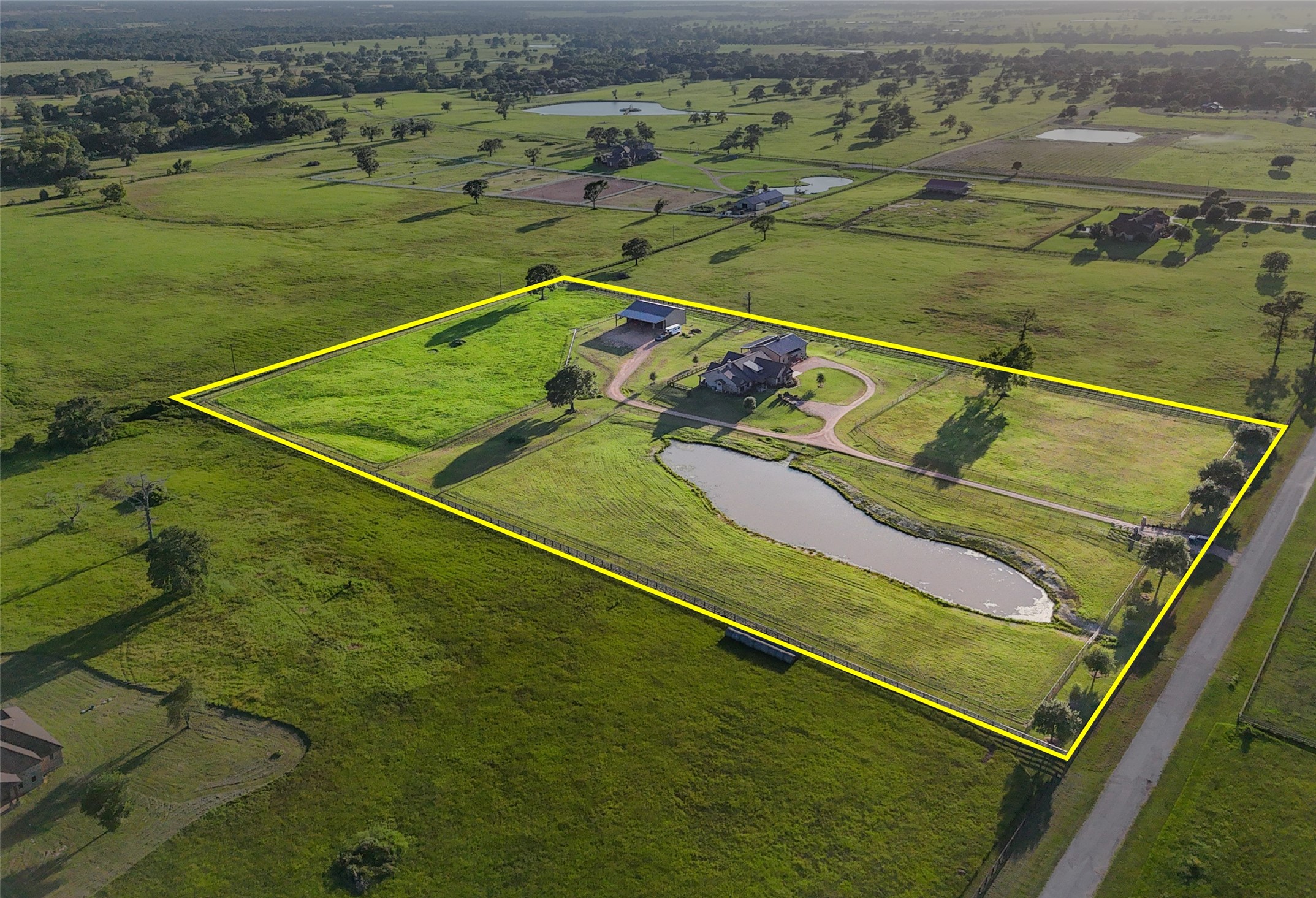 30163 High Spirit Ranch Road Hempstead, TX 77445 - Photo 4 of 47 An aerial perspective highlights the
full scope of the fenced property,
showcasing a private pond, gravel
driveway, and well-planned
improvements including a dedicated
shop and a horse barn with living
quarters.
