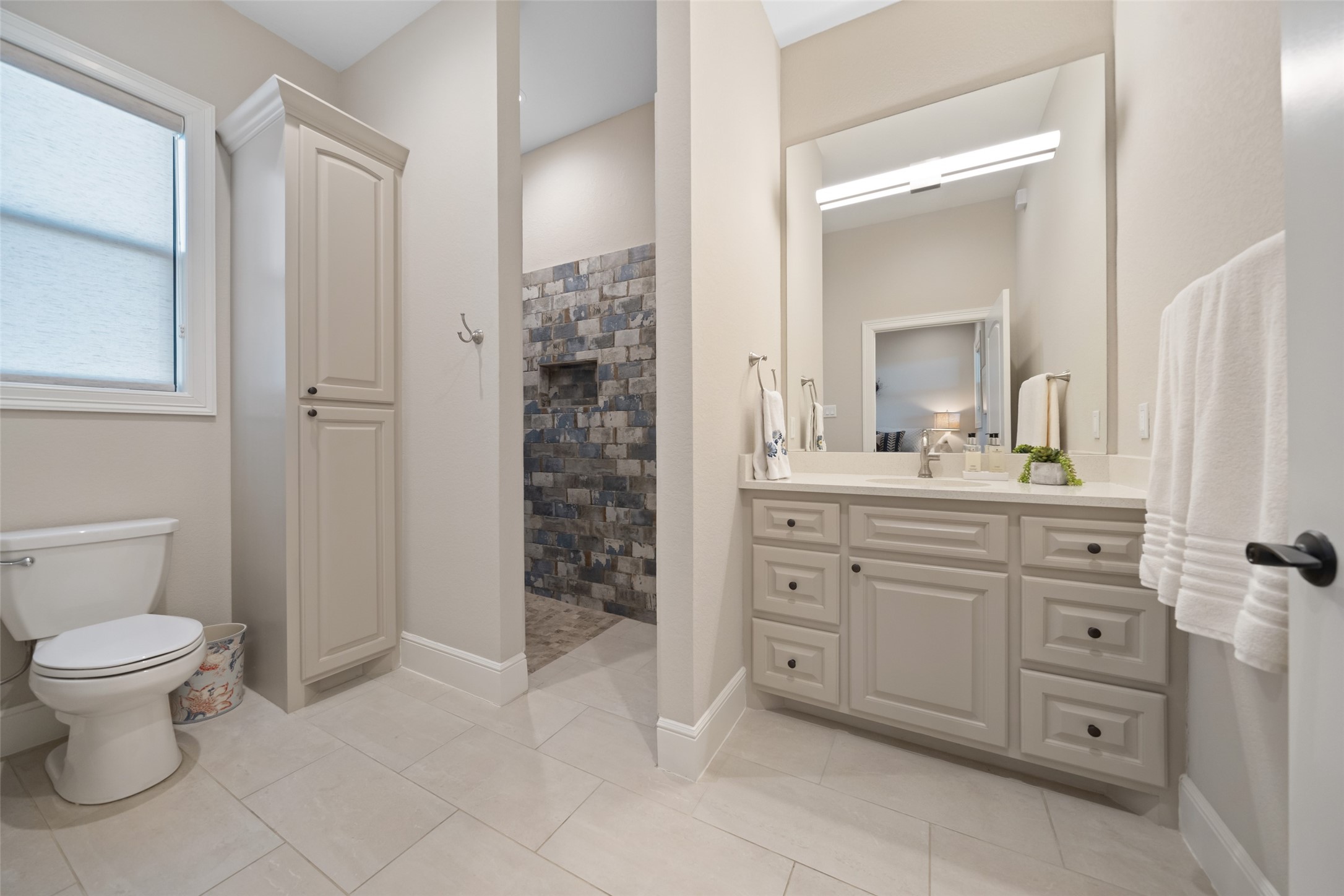 30163 High Spirit Ranch Road Hempstead, TX 77445 - Photo 42 of 47 A full en suite bath includes a walk-in
shower with unique stonework tile,
extended vanity, and built-in storage
cabinet enhancing the guest
bedroom.