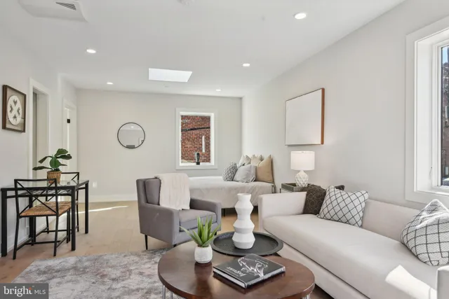 a living room with furniture a flat screen tv and a refrigerator