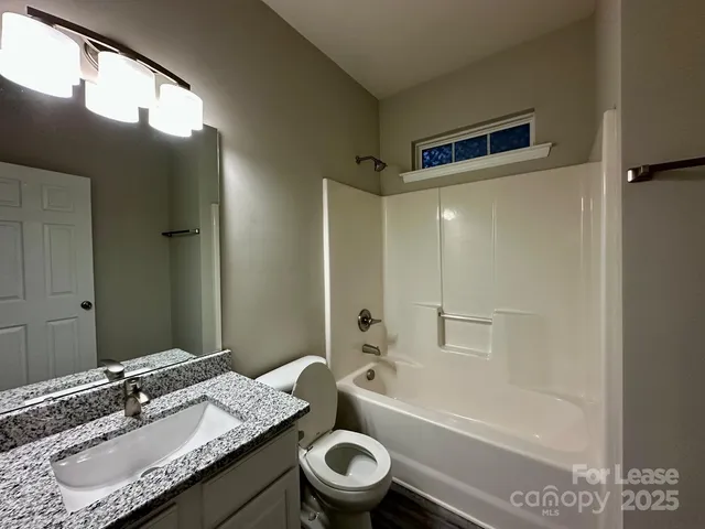a bathroom with a granite countertop sink toilet a large mirror a bathtub and shower