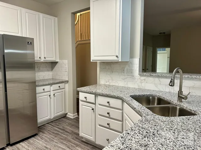 a kitchen with granite countertop a sink stainless steel appliances and cabinets