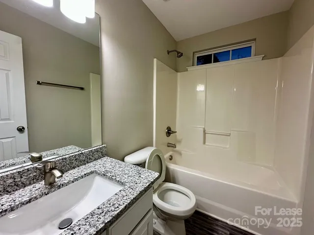 a bathroom with a granite countertop bathtub sink vanity mirror and toilet
