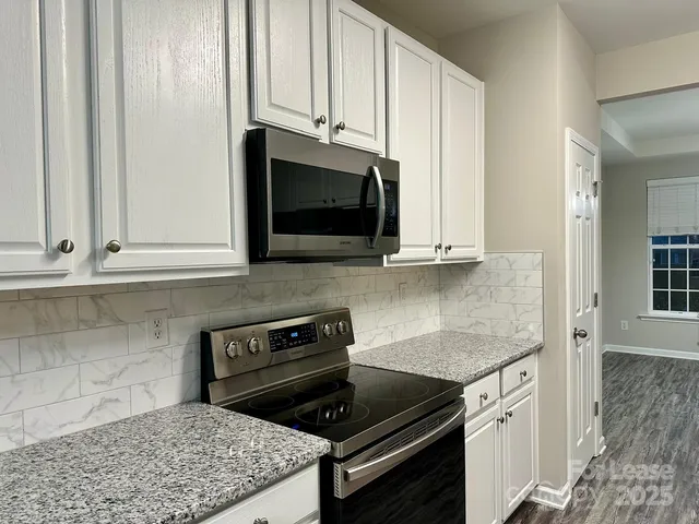 a kitchen with stainless steel appliances granite countertop white cabinets and a stove