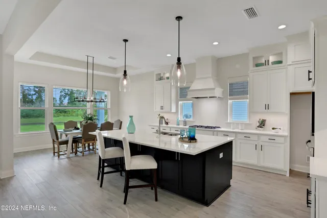 a kitchen with stainless steel appliances kitchen island granite countertop a table chairs and a wooden floor