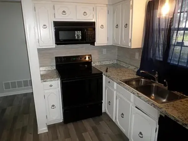 a kitchen with granite countertop white cabinets and black appliances