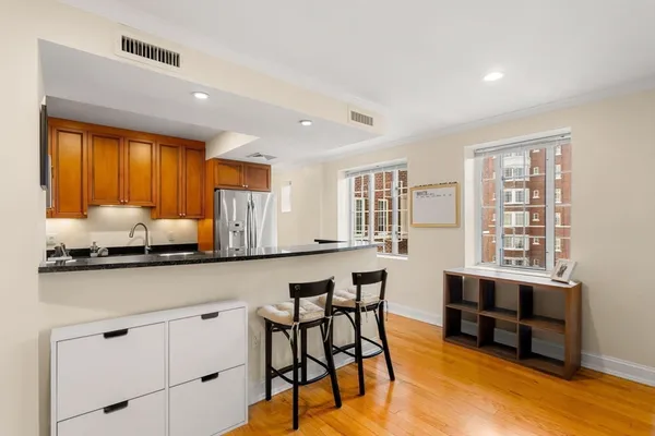 a kitchen with stainless steel appliances kitchen island granite countertop a table chairs in it and wooden floors