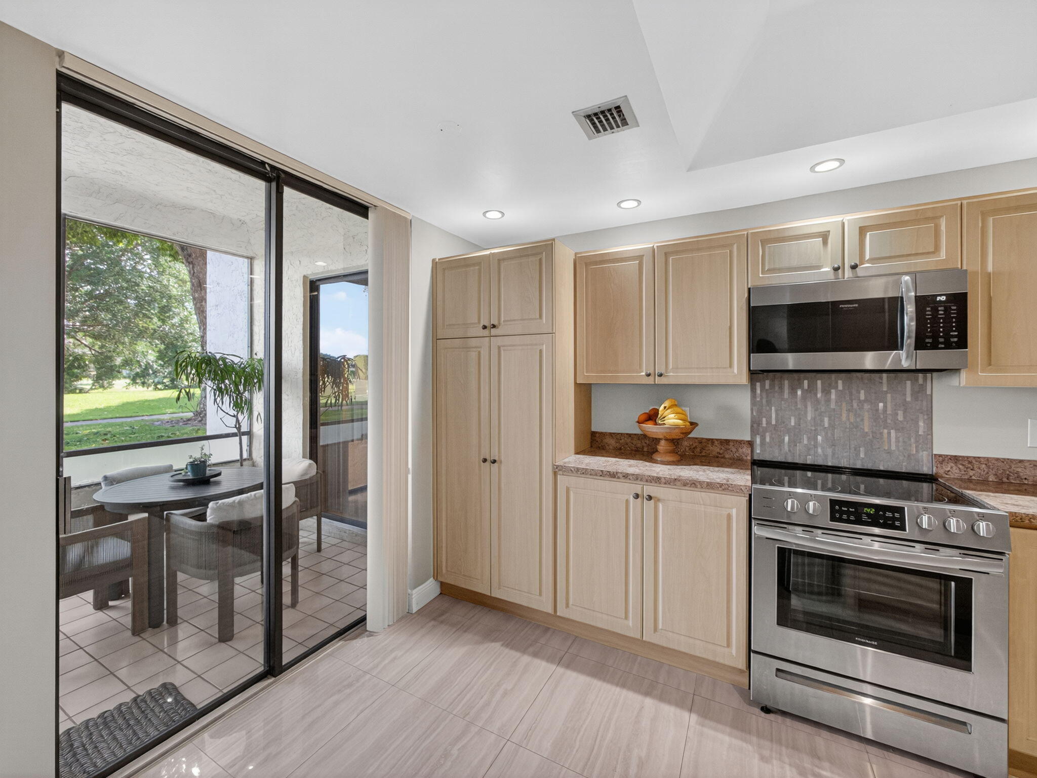 7472 La Paz Boulevard, Unit 109 Boca Raton, FL 33433 - Photo 12 of 29 a kitchen with kitchen island granite countertop a stove and a refrigerator