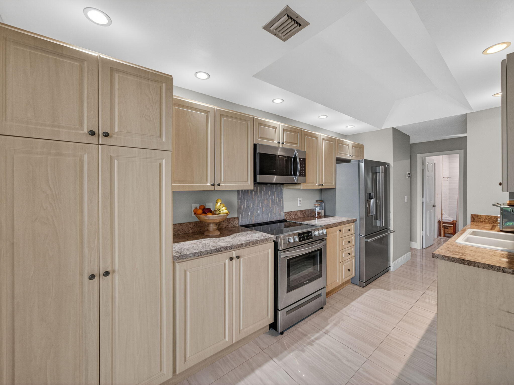 7472 La Paz Boulevard, Unit 109 Boca Raton, FL 33433 - Photo 10 of 29 a kitchen with white cabinets and stainless steel appliances
