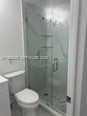 a white toilet sitting next to a shower