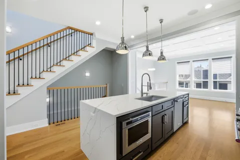 a large kitchen with granite countertop a large counter top a sink stainless steel appliances and cabinets