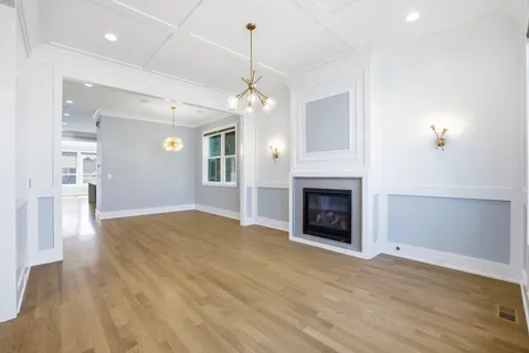 a view of a livingroom with a fireplace a chandelier and wooden floor