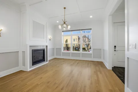 an empty room with wooden floor fireplace and windows
