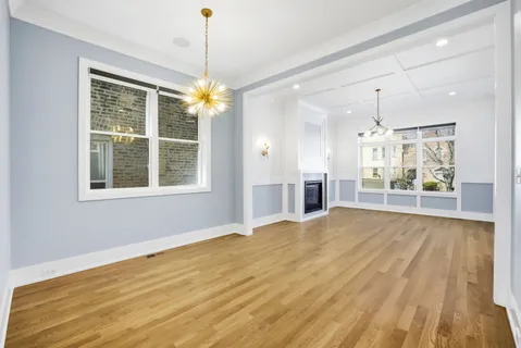 a view of an empty room with window and wooden floor
