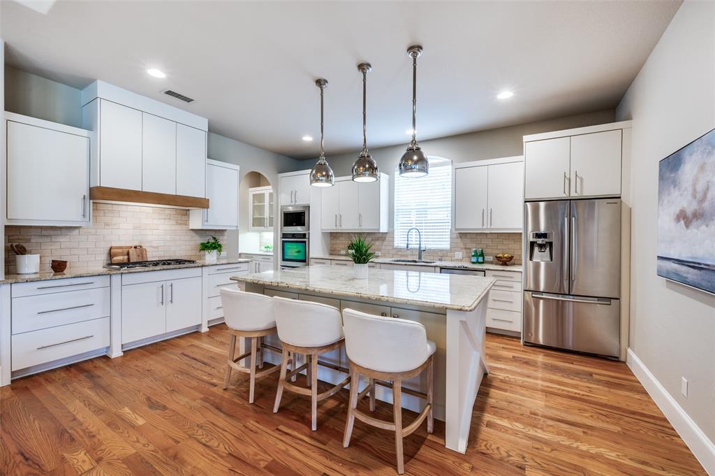 2168 Dampton Drive Frisco, TX 75033 - Photo 7 of 31 a kitchen with stainless steel appliances a dining table chairs sink refrigerator and microwave
