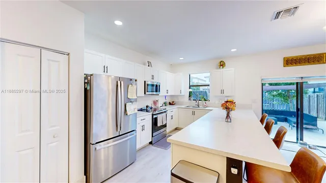a kitchen with stainless steel appliances refrigerator dining table and chairs