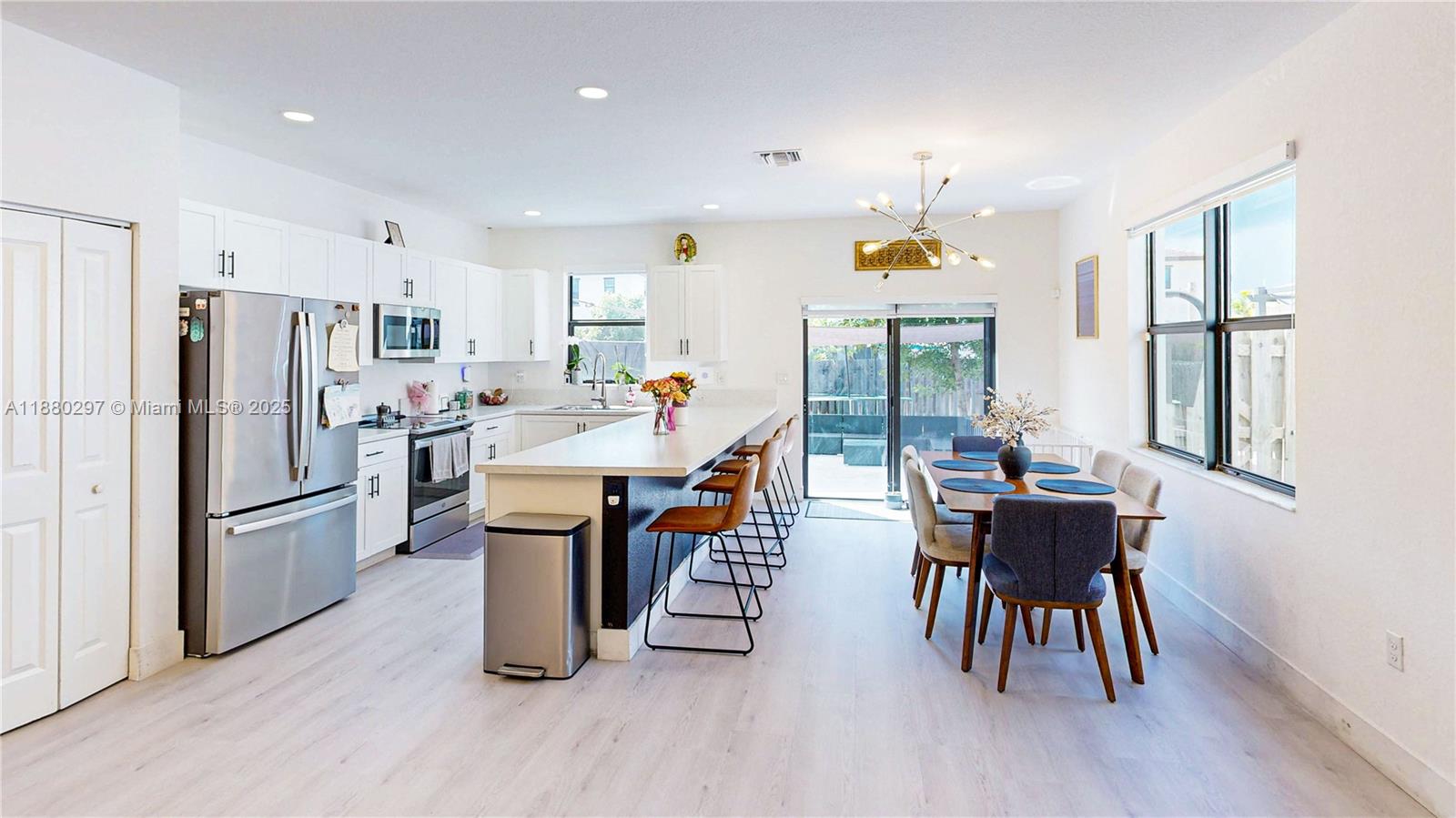 24902 Southwest 107th Avenue Homestead, FL 33032 - Photo 16 of 73 a kitchen with stainless steel appliances a dining table chairs refrigerator and wooden floor