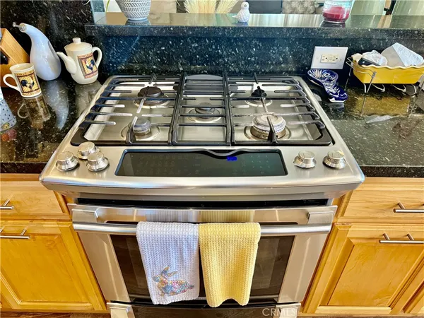 a kitchen with stainless steel appliances granite countertop a stove top oven a sink dishwasher a dining table and chairs with wooden floor