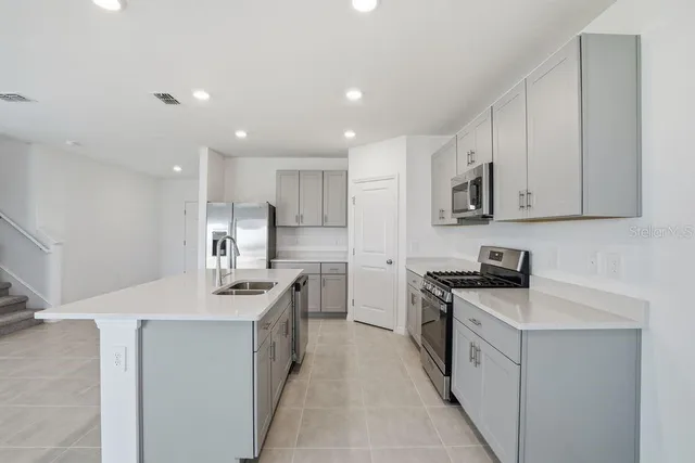 a kitchen with stainless steel appliances granite countertop a sink stove oven and white cabinets
