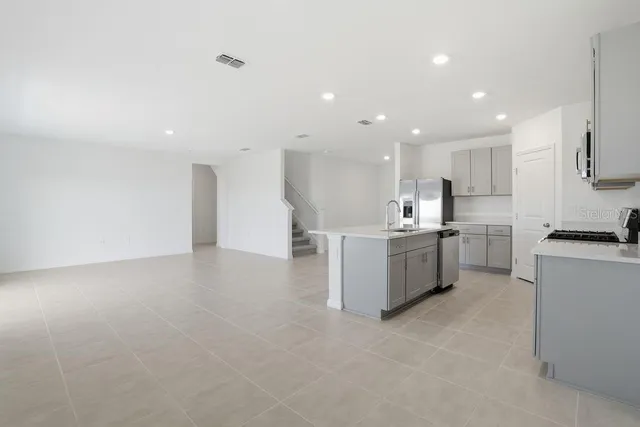 a large kitchen with a large counter top a sink stainless steel appliances and cabinets