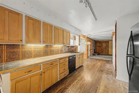 a kitchen with stainless steel appliances granite countertop a refrigerator a sink dishwasher a stove and white countertops with wooden floor