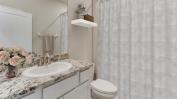 a bathroom with a granite countertop sink a toilet and a mirror