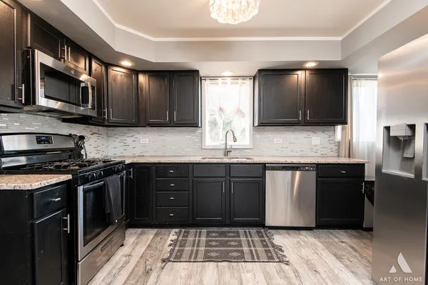 a kitchen with stainless steel appliances granite countertop a stove a sink and a microwave